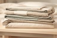 Coordinated duvet cover and sheet set folded together in soft neutral colours