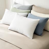 Supportive pillows in different shapes and fabrics arranged on a neatly made bed