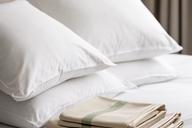 Plump hotel-style pillows and folded pillowcases arranged on fresh white bedding